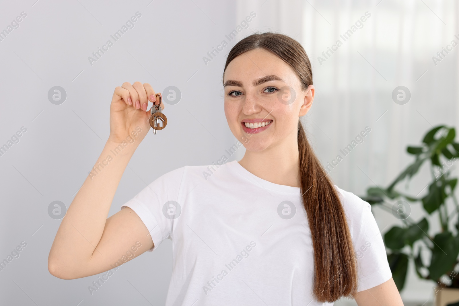 Happy woman with key of her new house indoors Photo of Happy woman with key of her new house indoors