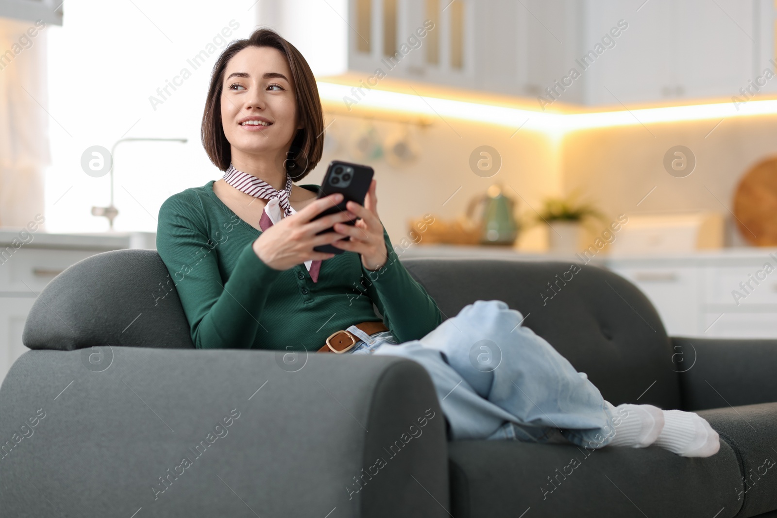 Woman using modern smartphone on sofa at home. Space for text Photo of Woman using modern smartphone on sofa at home. Space for text