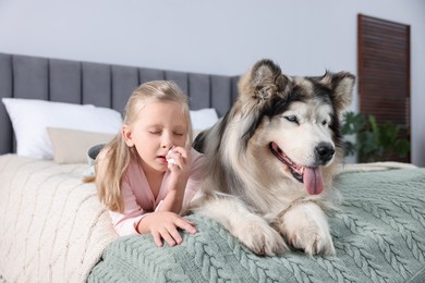 Photo of Girl suffering from allergy with her dog on bed at home