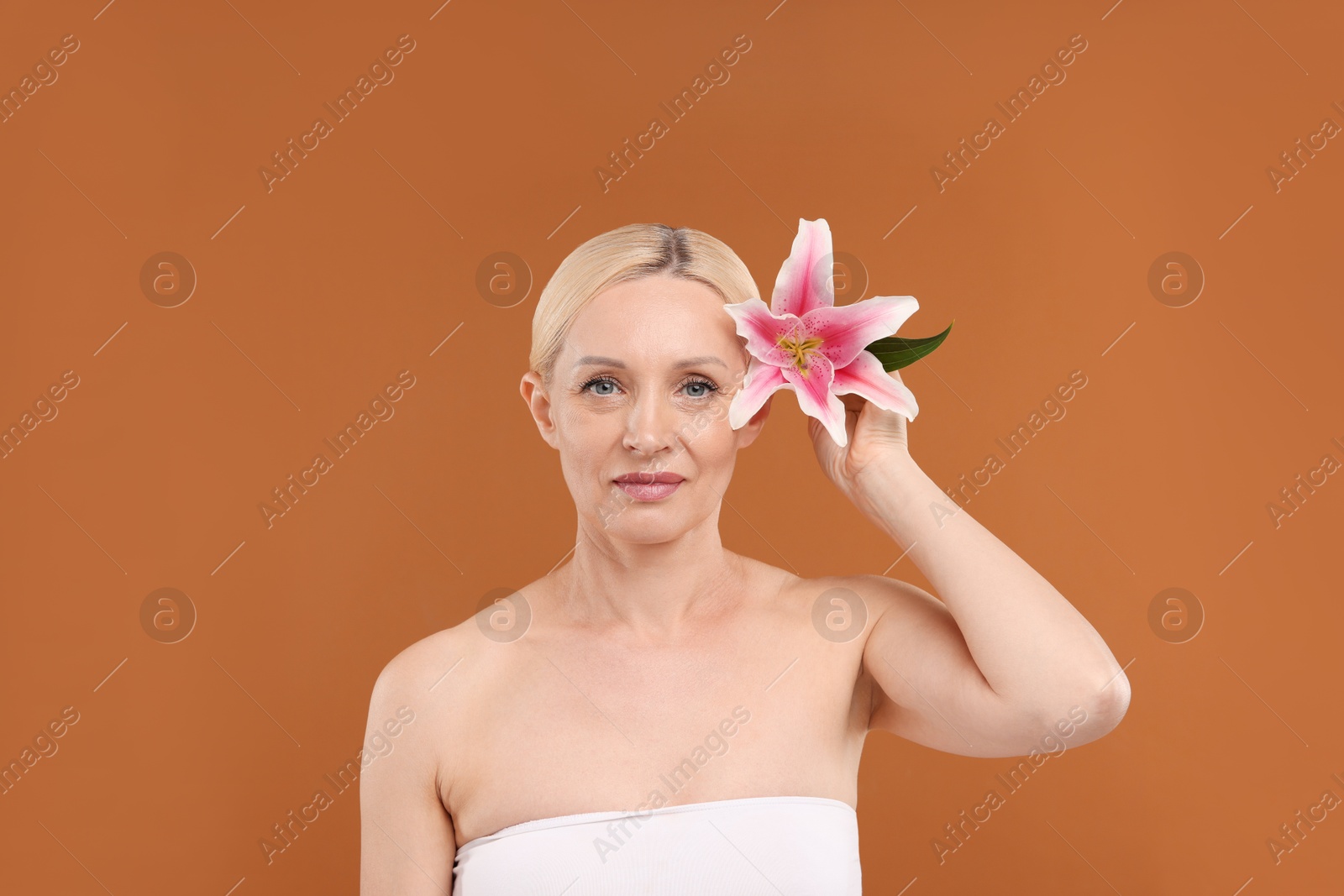 Beautiful woman with lily flower on brown background Photo of Beautiful woman with lily flower on brown background