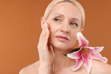 Photo of Beautiful woman with lily flower on brown background, closeup