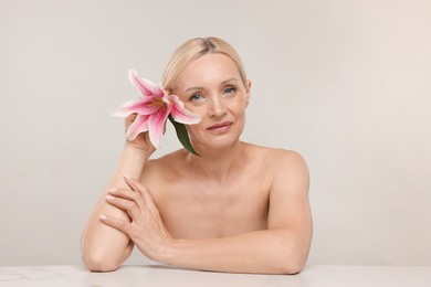 Photo of Beautiful woman with lily flower on light background
