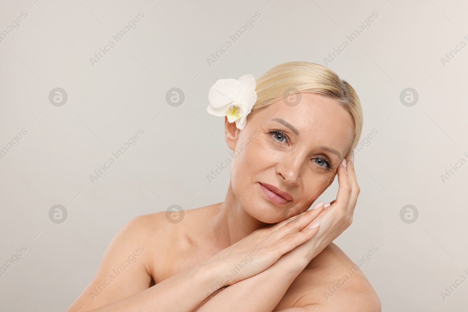Beautiful woman with orchid flower on light background. Space for text Photo of Beautiful woman with orchid flower on light background. Space for text
