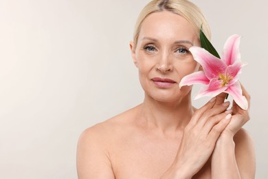 Photo of Beautiful woman with lily flower on light background. Space for text