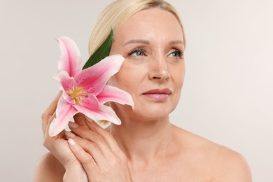 Photo of Beautiful woman with lily flower on light background, closeup