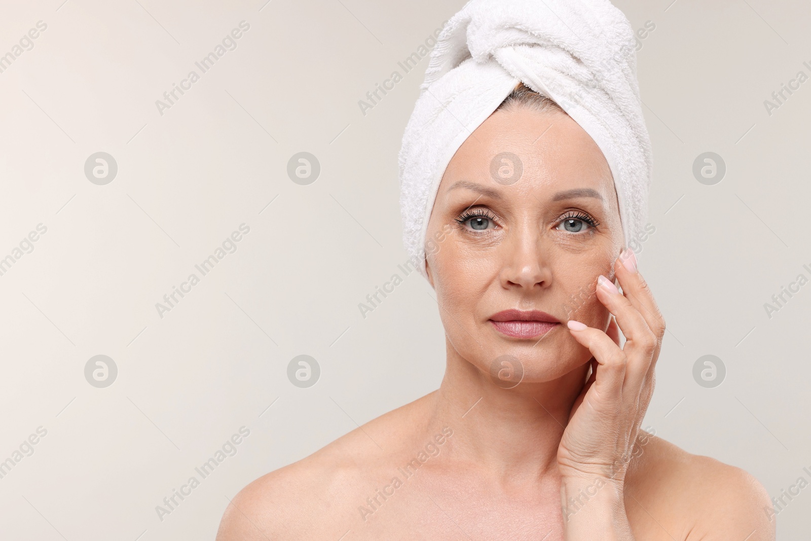 Beautiful woman with towel wrapped on her head against light background. Space for text Photo of Beautiful woman with towel wrapped on her head against light background. Space for text