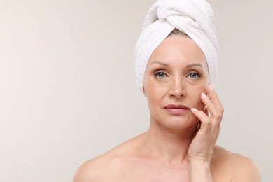 Photo of Beautiful woman with towel wrapped on her head against light background. Space for text