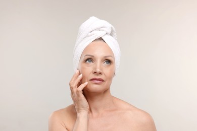 Photo of Beautiful woman with towel wrapped on her head against light background