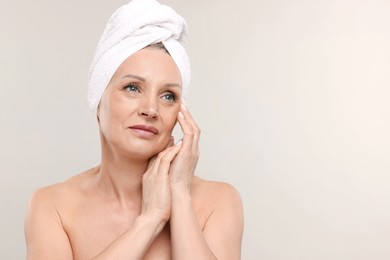 Photo of Beautiful woman with towel wrapped on her head against light background. Space for text