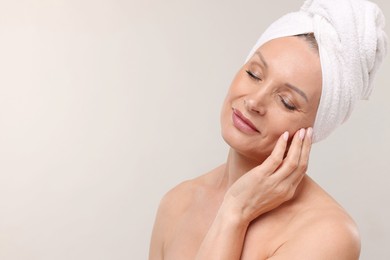 Photo of Beautiful woman with towel wrapped on her head against light background. Space for text