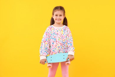 Photo of Little girl with penny board on yellow background
