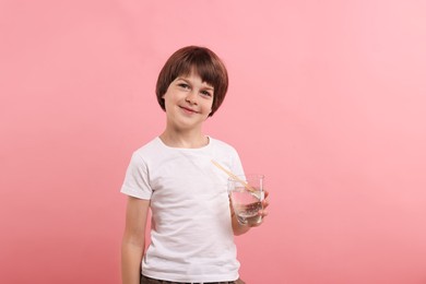 Photo of Cute little boy with glass of refreshing soda drink on pink background