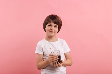 Photo of Cute little boy with glass of refreshing soda drink on pink background