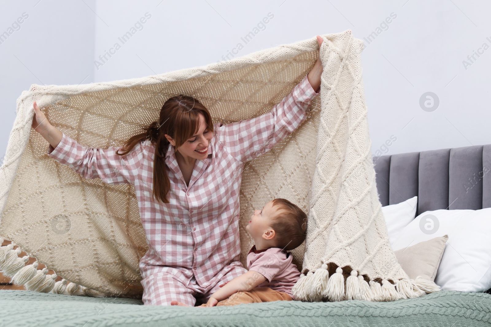 Happy mother playing with her son on bed at home Photo of Happy mother playing with her son on bed at home
