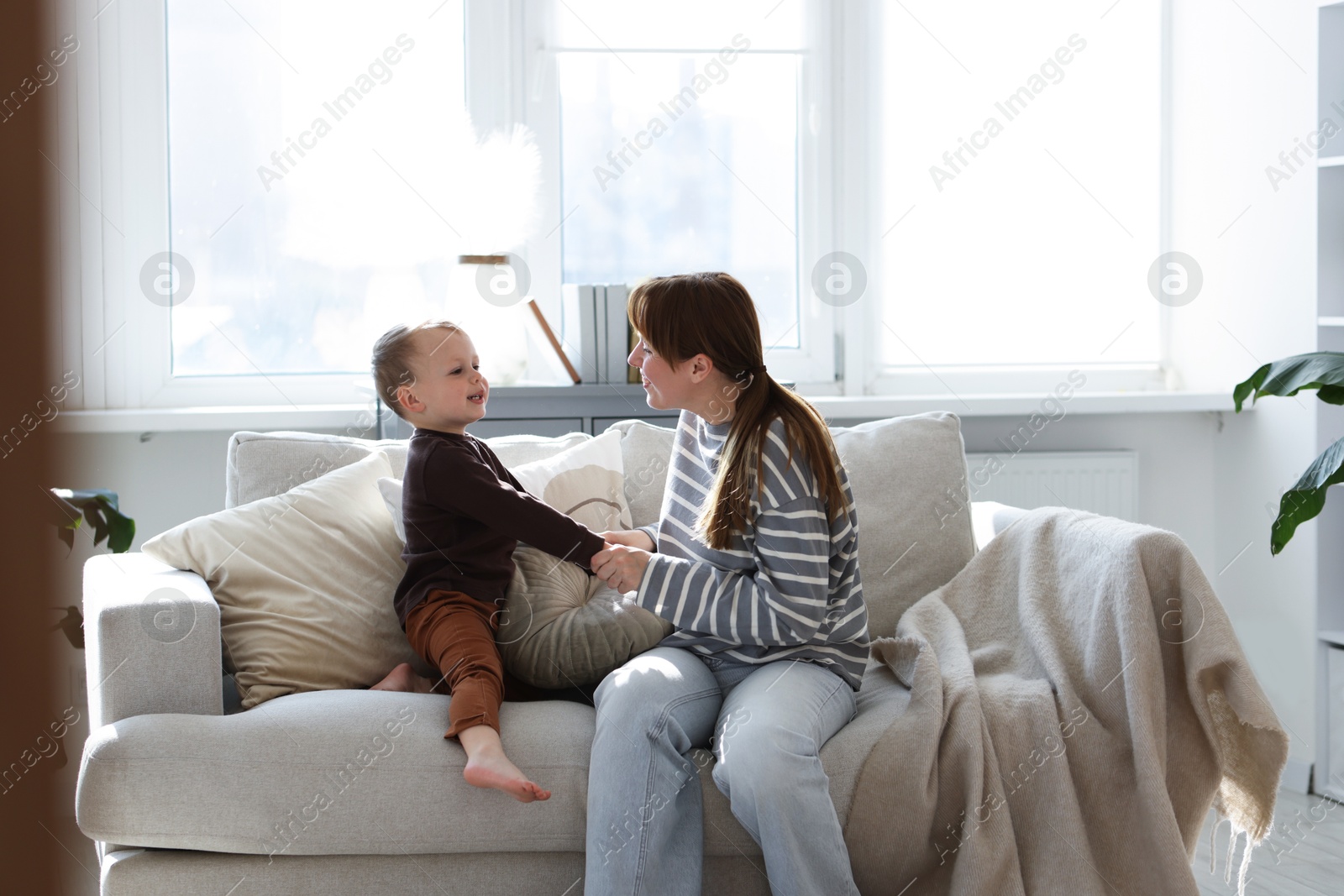 Happy mother spending time together with her son on sofa at home Photo of Happy mother spending time together with her son on sofa at home