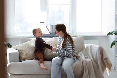 Photo of Happy mother spending time together with her son on sofa at home