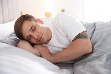 Photo of Young man lying on bed with soft mattress at home