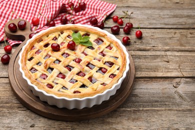 Photo of Tasty cherry pie on wooden table, closeup. Space for text