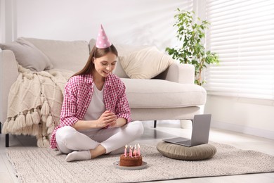 Photo of Birthday celebration. Happy woman with tasty cake having video call via laptop at home