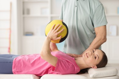 Photo of Doctor and patient exercising with medicine ball in clinic