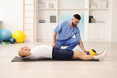 Photo of Doctor and patient exercising with medicine ball in clinic