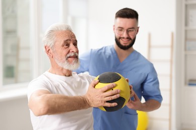 Photo of Doctor and patient exercising with medicine ball in clinic, selective focus