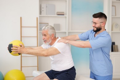 Photo of Doctor and patient exercising with medicine ball in clinic