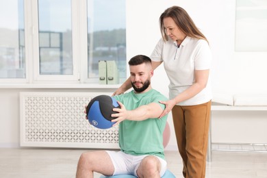 Photo of Doctor and patient exercising with medicine ball in clinic