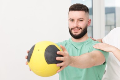 Photo of Doctor and patient exercising with medicine ball in clinic