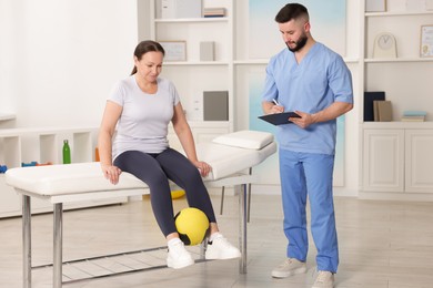 Photo of Doctor and patient exercising with medicine ball in clinic
