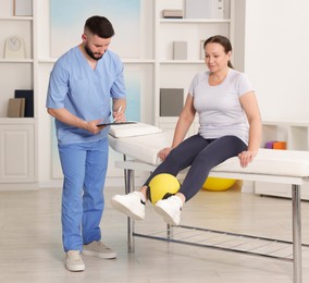 Photo of Doctor and patient exercising with medicine ball in clinic