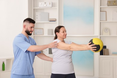 Photo of Doctor and patient exercising with medicine ball in clinic