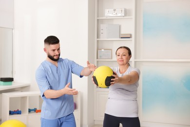 Photo of Doctor and patient exercising with medicine ball in clinic
