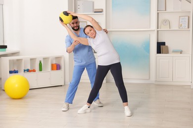 Photo of Doctor and patient exercising with medicine ball in clinic