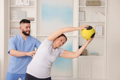 Photo of Doctor and patient exercising with medicine ball in clinic