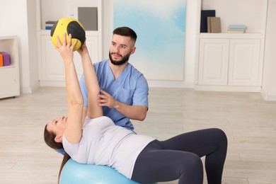 Photo of Doctor and patient exercising with medicine ball in clinic