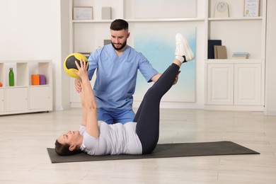 Photo of Doctor and patient exercising with medicine ball in clinic