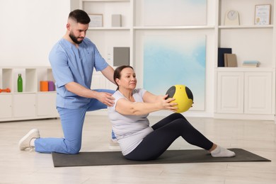 Photo of Doctor and patient exercising with medicine ball in clinic