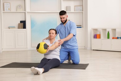 Photo of Doctor and patient exercising with medicine ball in clinic