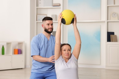 Photo of Doctor and patient exercising with medicine ball in clinic
