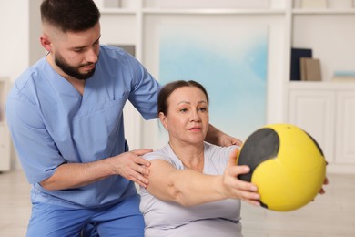 Photo of Doctor and patient exercising with medicine ball in clinic