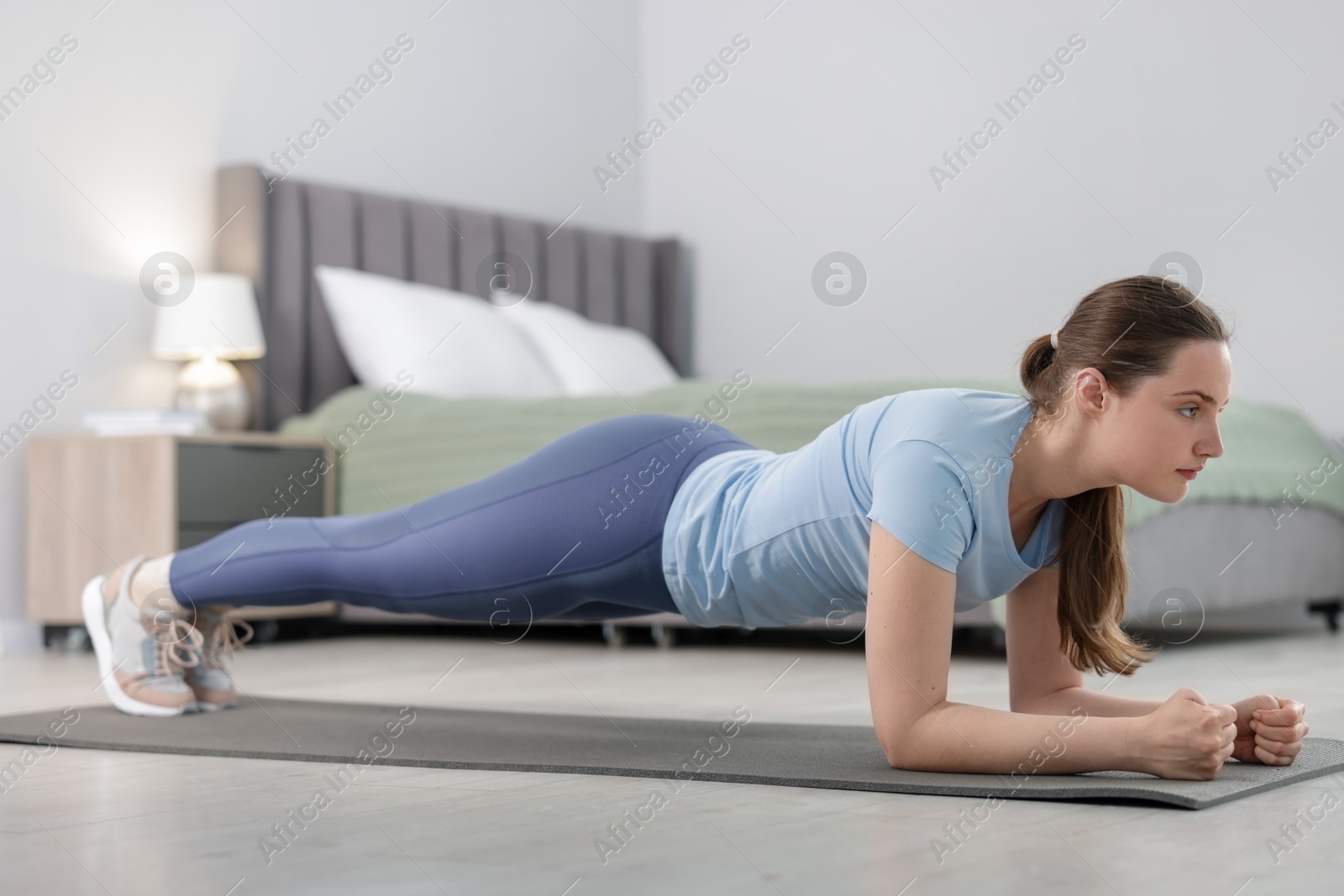 Woman in sportswear doing plank exercise at home Photo of Woman in sportswear doing plank exercise at home