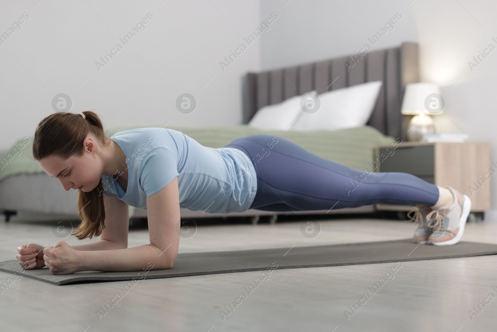 Woman in sportswear doing plank exercise at home Photo of Woman in sportswear doing plank exercise at home