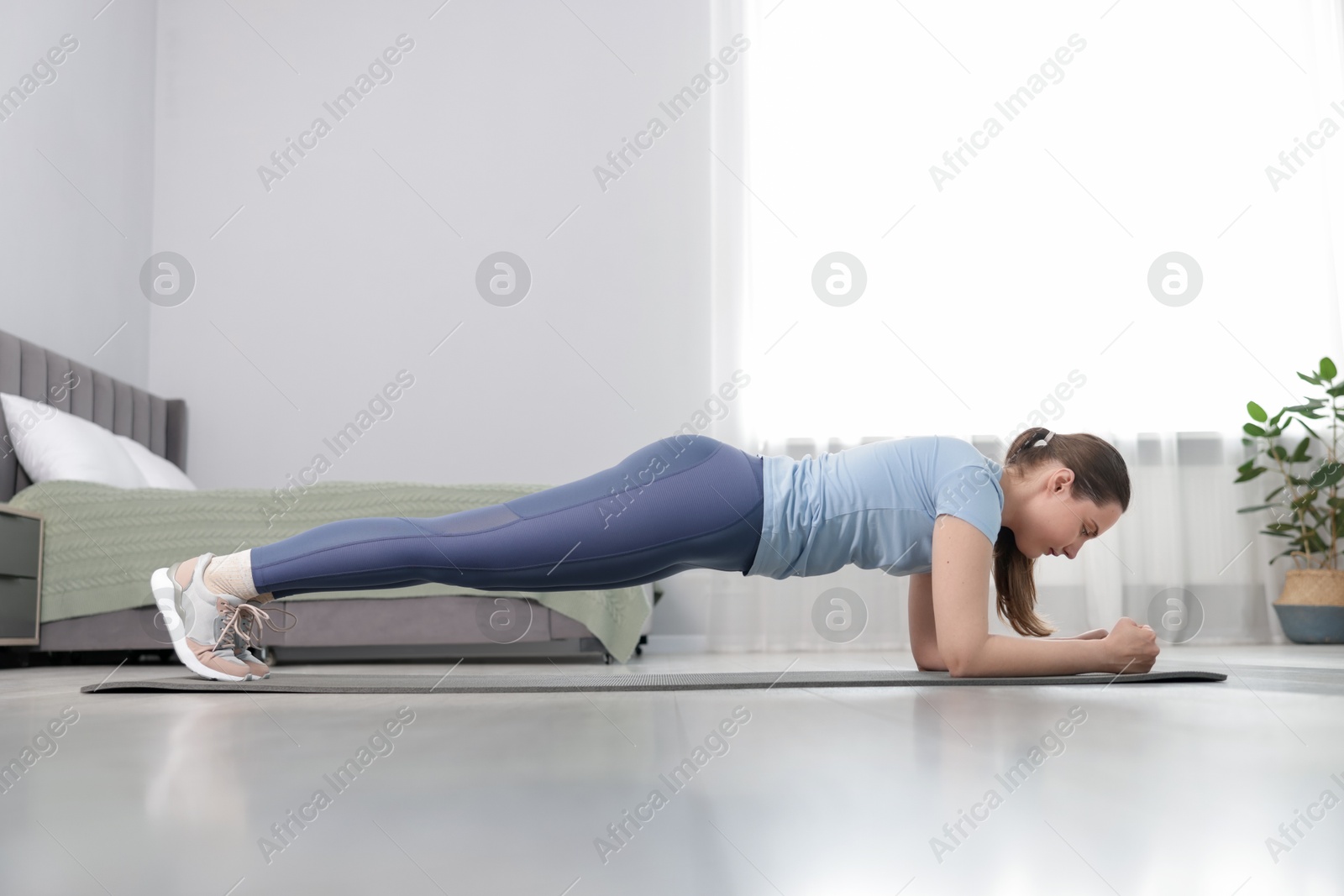 Woman in sportswear doing plank exercise at home Photo of Woman in sportswear doing plank exercise at home