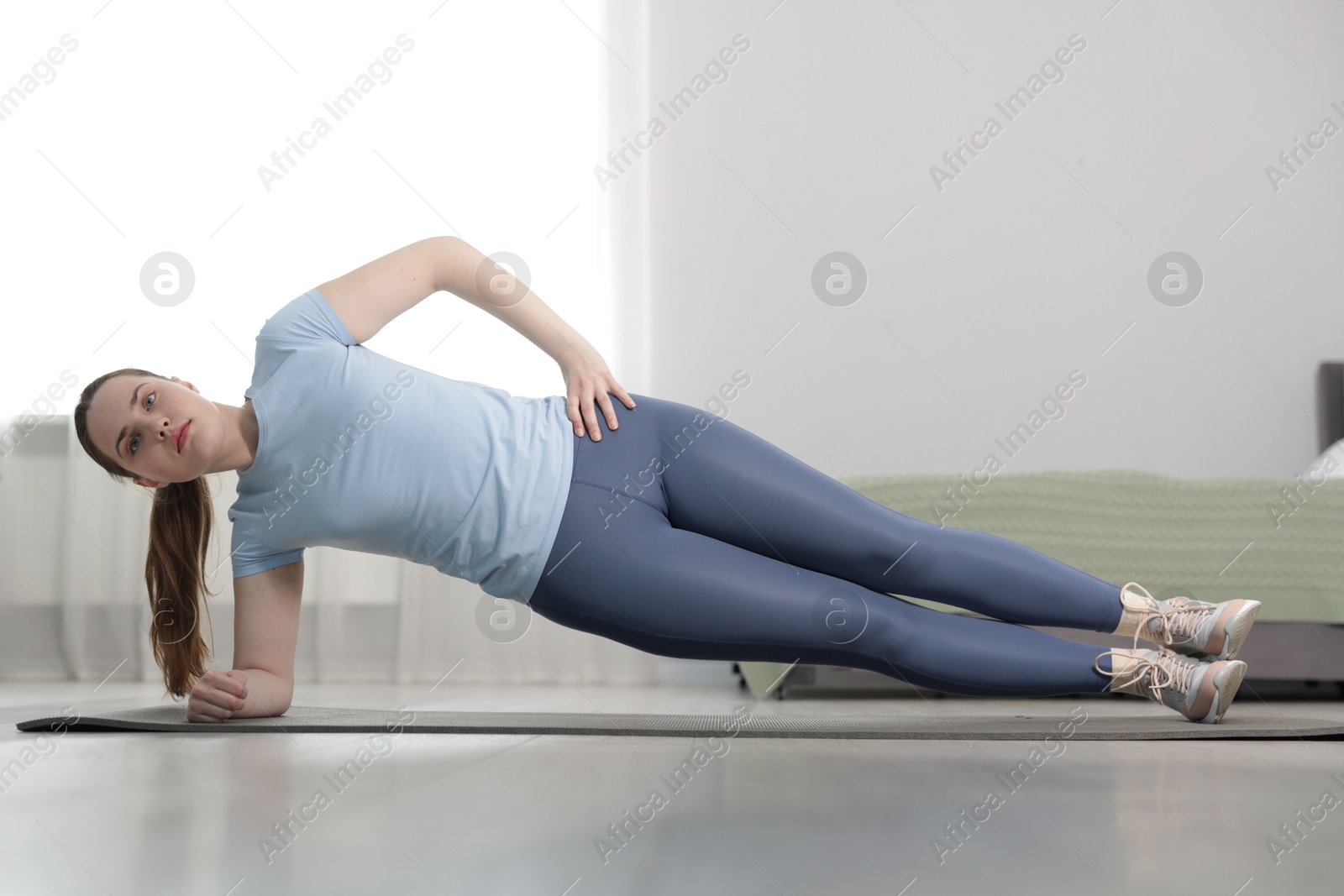 Woman in sportswear doing plank exercise at home Photo of Woman in sportswear doing plank exercise at home
