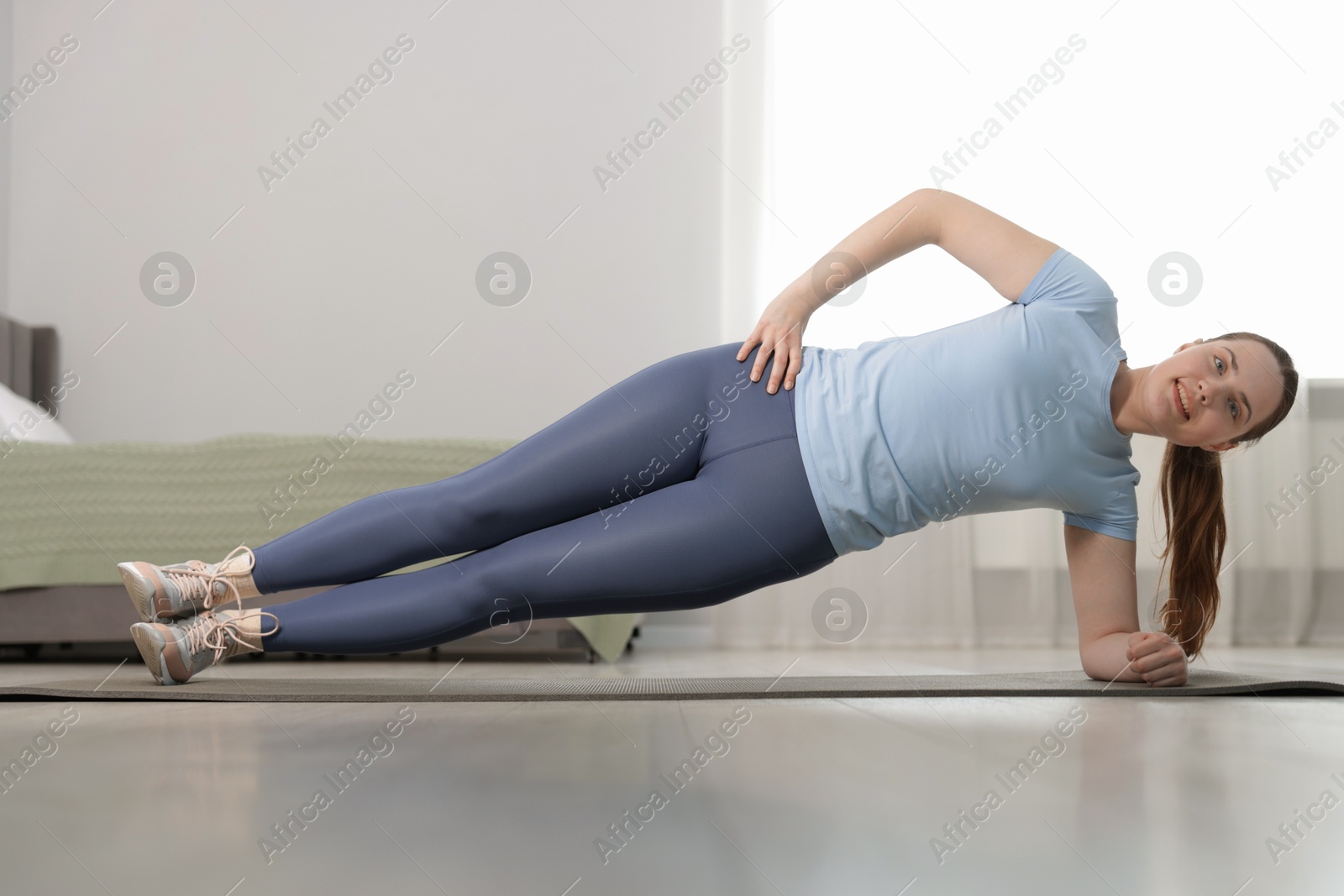 Woman in sportswear doing plank exercise at home Photo of Woman in sportswear doing plank exercise at home