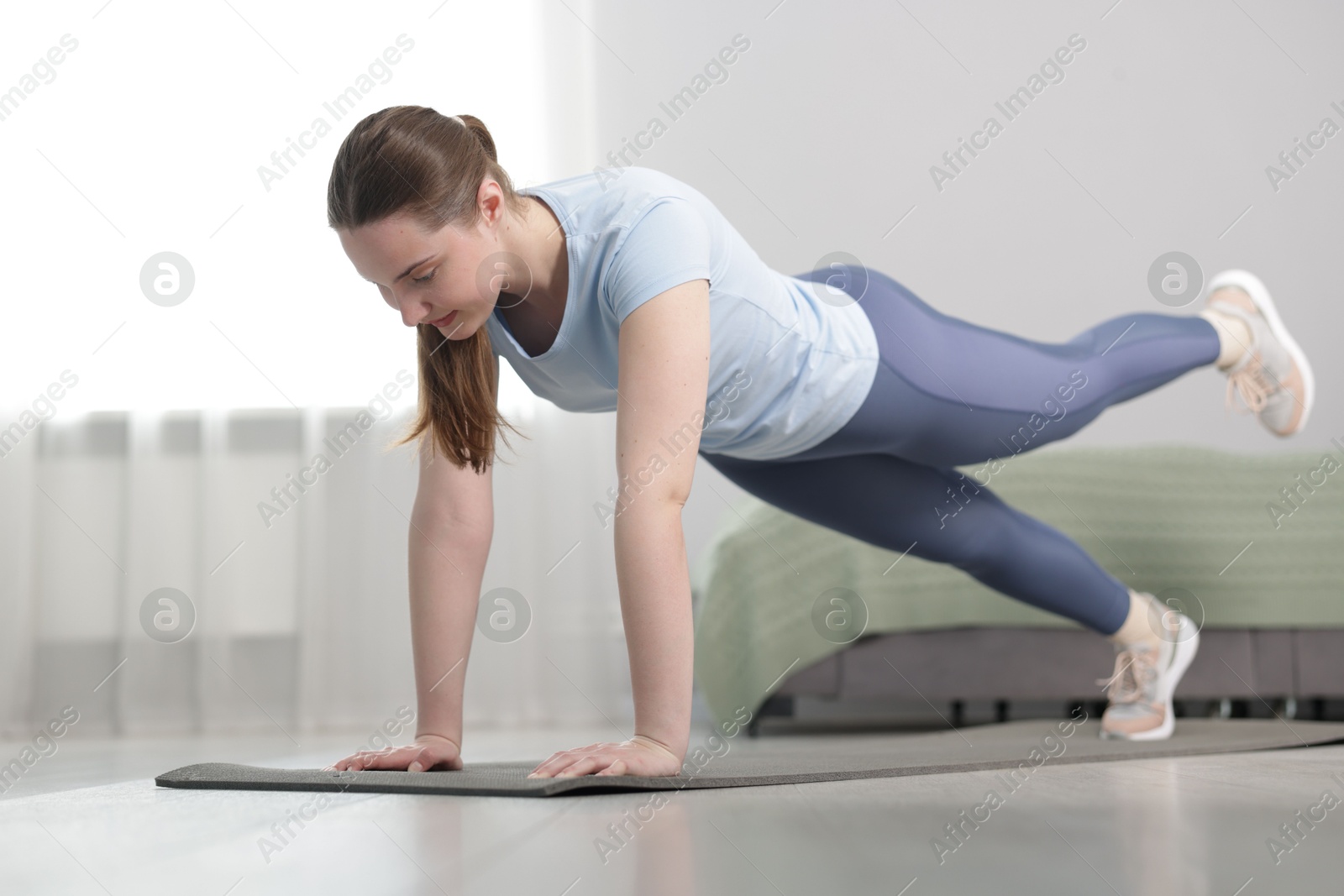 Woman in sportswear doing plank exercise at home Photo of Woman in sportswear doing plank exercise at home