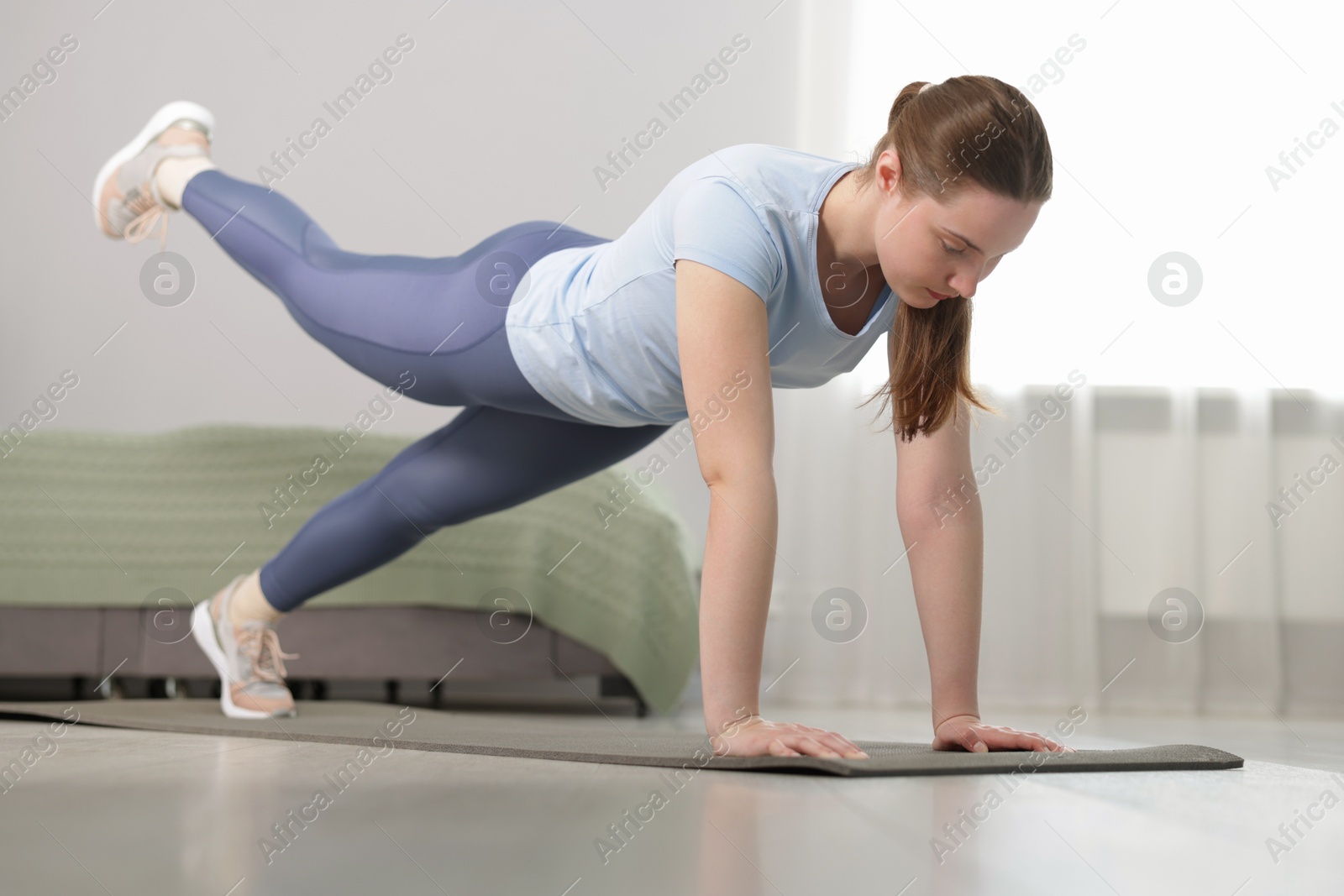 Woman in sportswear doing plank exercise at home Photo of Woman in sportswear doing plank exercise at home