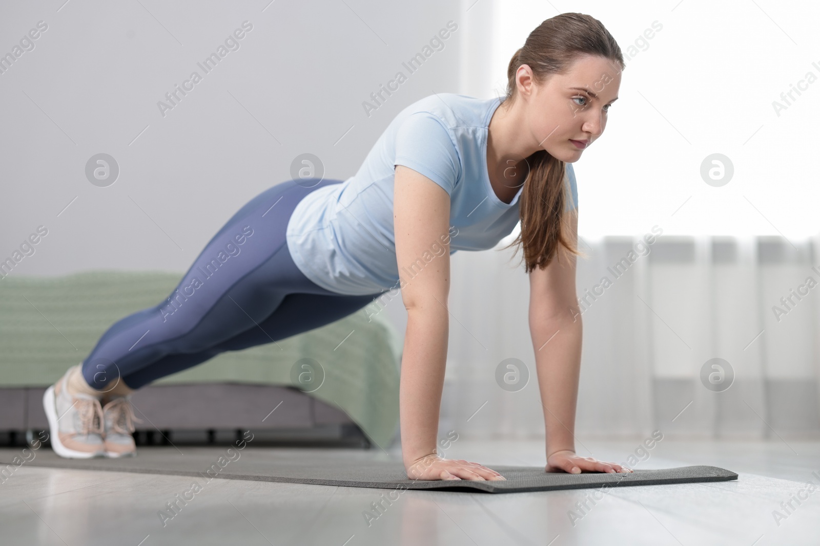 Woman in sportswear doing plank exercise at home Photo of Woman in sportswear doing plank exercise at home