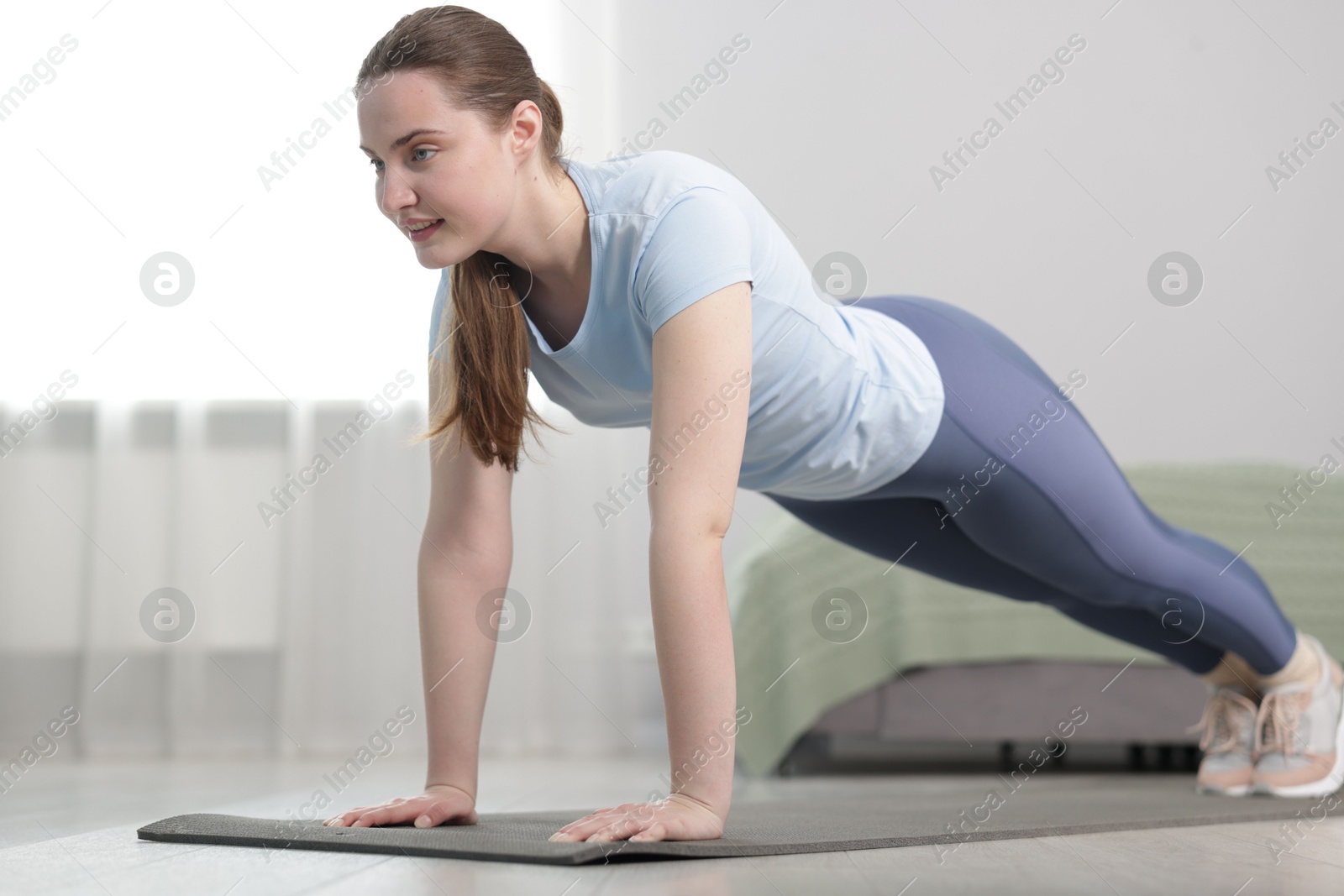 Woman in sportswear doing plank exercise at home Photo of Woman in sportswear doing plank exercise at home